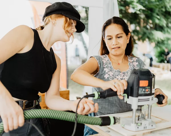 Zwei Menschen bearbeiten Holz mit einer Maschine