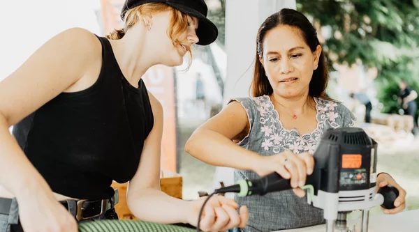 Zwei Menschen bearbeiten Holz mit einer Maschine