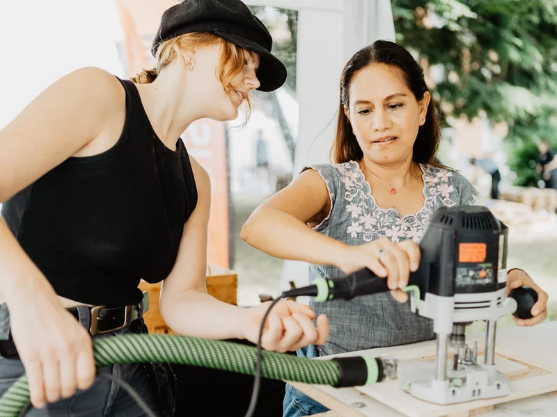 Zwei Menschen bearbeiten Holz mit einer Maschine