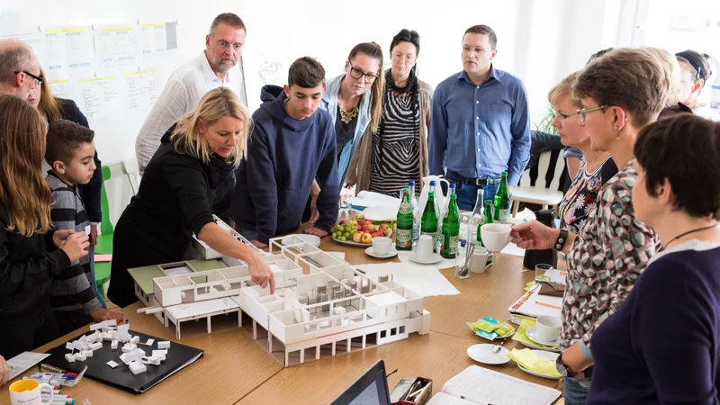 Große Menschengruppe schaut auf ein Architekturmodell