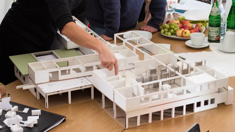 Große Menschengruppe schaut auf ein Architekturmodell