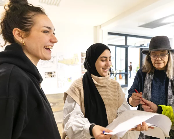 Lachende Menschen stehen und schreiben etwas auf eine Liste