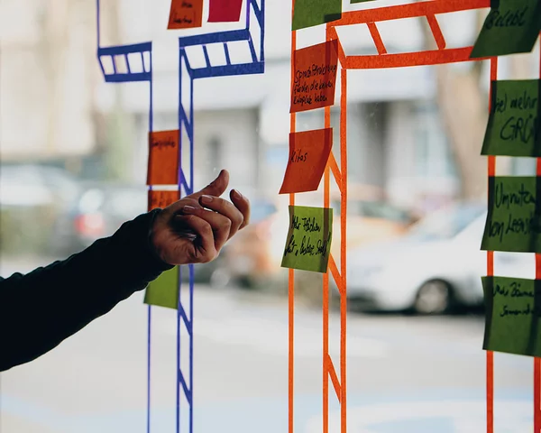 Menschen kleben Post-Its auf eine bemalte Glasscheibe