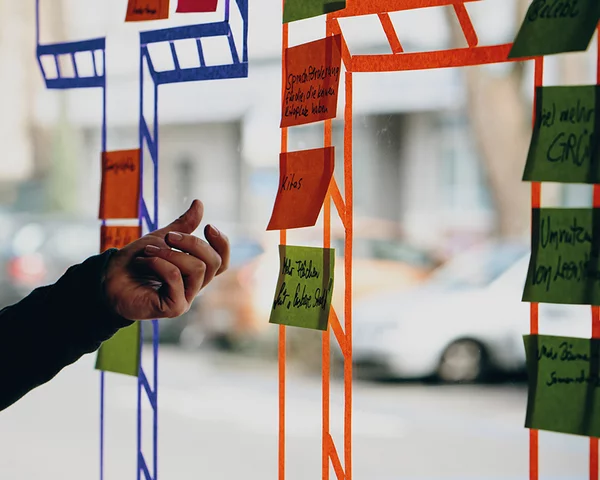 Menschen kleben Post-Its auf eine bemalte Glasscheibe