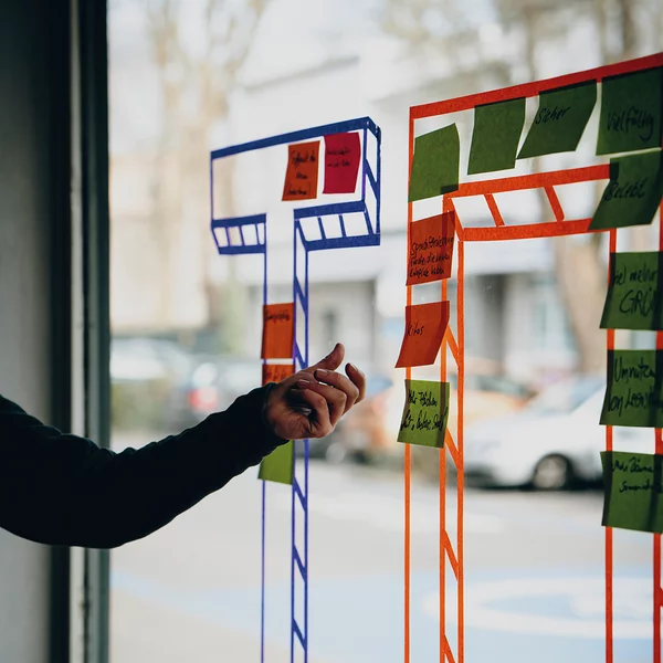 Menschen kleben Post-Its auf eine bemalte Glasscheibe