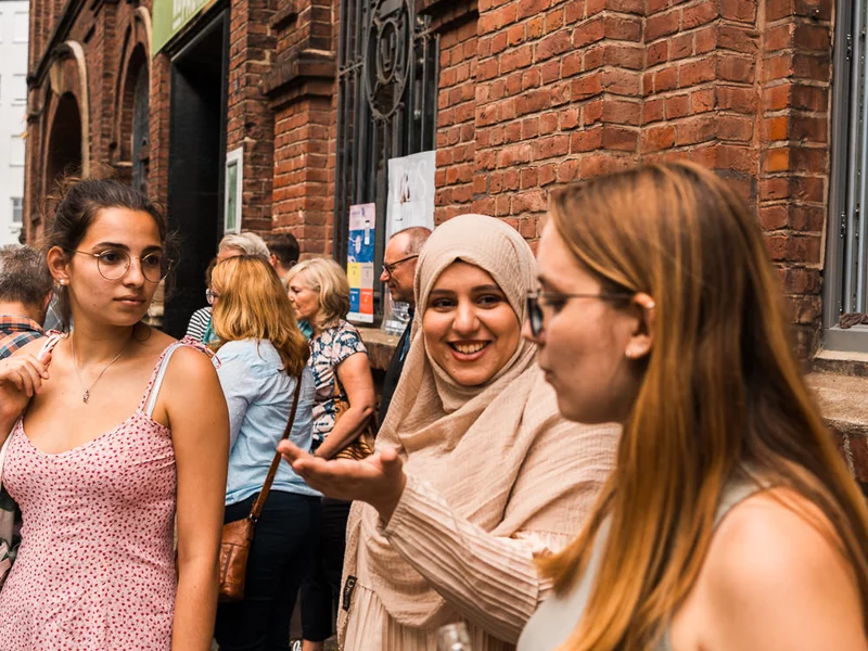 Eine Gruppe Frauen steht in der Sonne vor der KoFabrik in Bochum.
