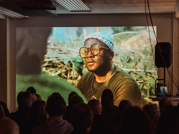 Menschen sitzen in einem verdunkelten Raum und schauen einen Film auf einer Leinwand