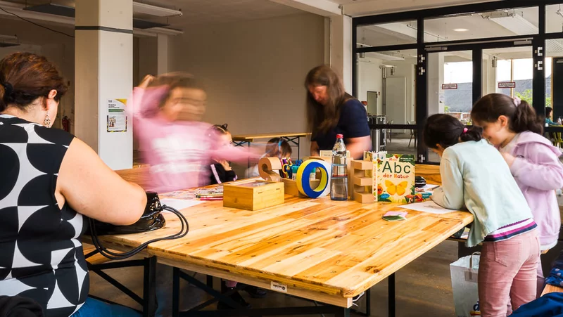 Kinder stehen mit Erwachsenen am Tisch und malen