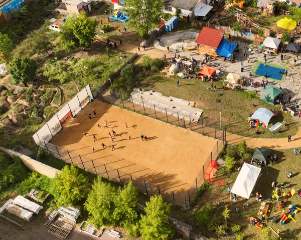 Drohnenaufnahme von dem Park FreiFeld in Halle Freiimfelde. Ein Bolzplatz, viele Menschen, im Hintergrund die angrenzende Wohnbebauung, links im Bild die Bahnschienen.