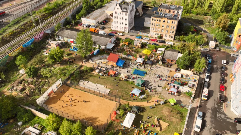 Drohnenaufnahme von dem Park FreiFeld in Halle Freiimfelde. Ein Bolzplatz, viele Menschen, im Hintergrund die angrenzende Wohnbebauung, links im Bild die Bahnschienen.