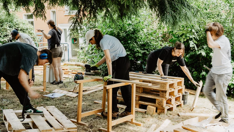 Menschen arbeiten draußen mit Holzbrettern