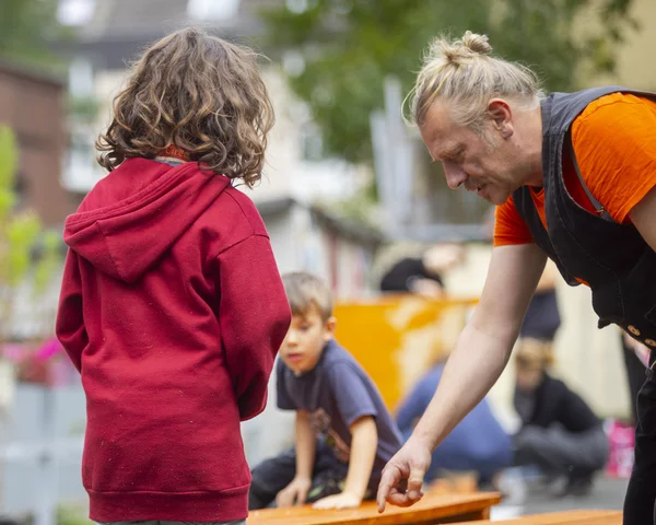Mann zeigt Kindern Schrauben auf einem Brett