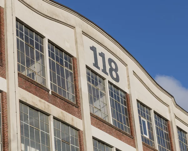 Außenansicht der Wiesenwerke, Wiesenstraße 118 in Wuppertal. Zu sehen ist eine Gebäudefassade mit großen FEnsterflächen und der Hausnummer 118 im Giebel vor blauem Himmel.