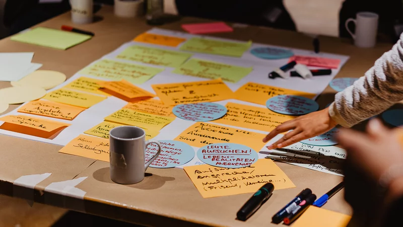 Post-Its, Papiere und Stifte sind auf einem Tisch