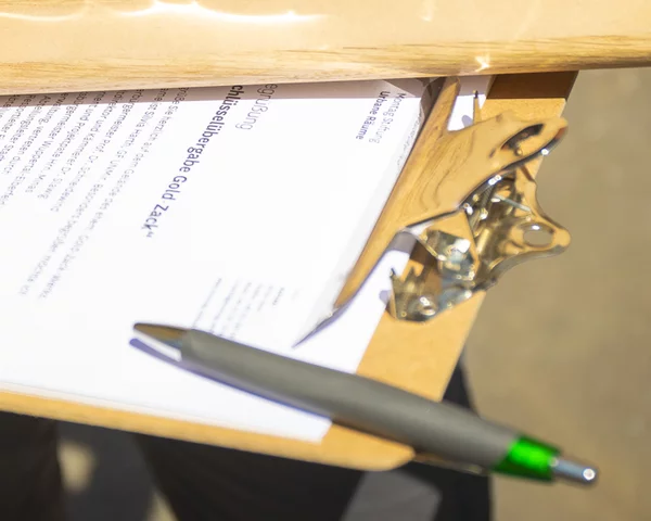 Mensch hält Holzobjekt über Dokument