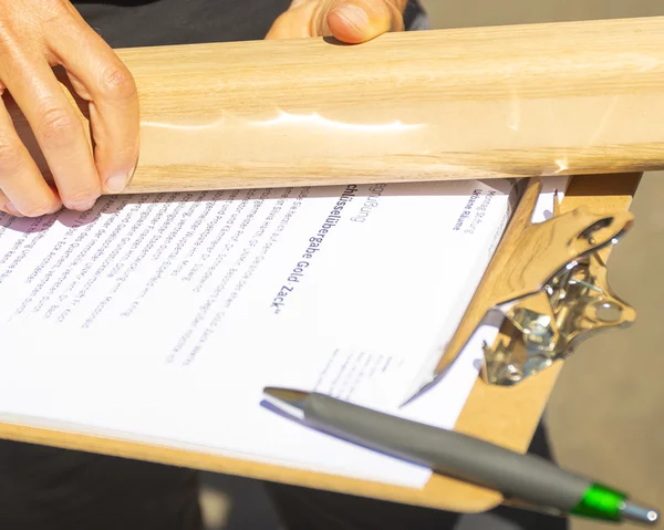 Mensch hält Holzobjekt über Dokument