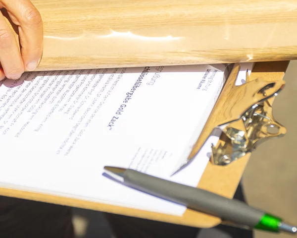 Mensch hält Holzobjekt über Dokument