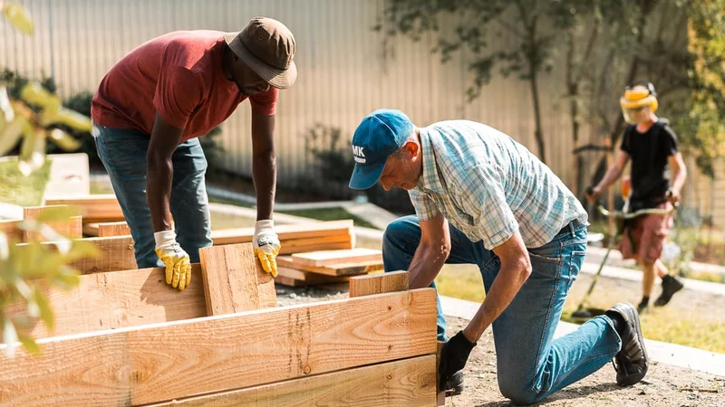 Menschen knien bei der Befestigung von Holzbrettern in einem Garten