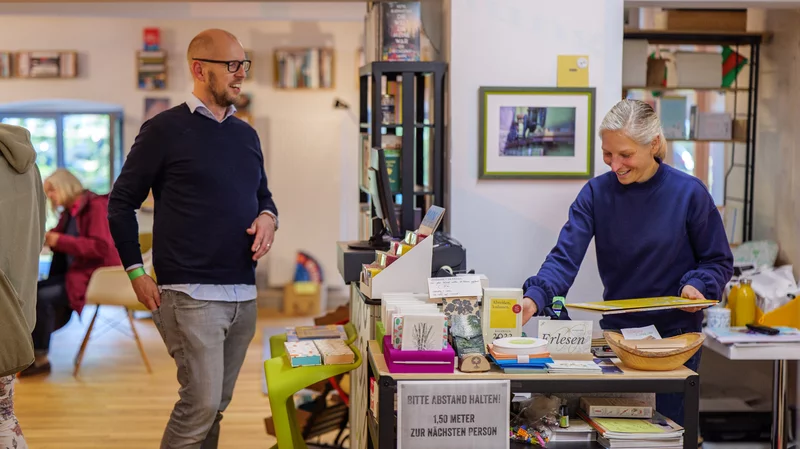 Mensch steht an Kasse in hellem Buchladen
