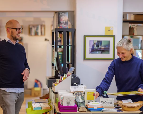 Mensch steht an Kasse in hellem Buchladen
