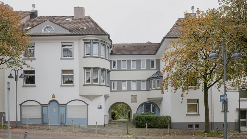 EIn Toreingang in der Siemensstraße am Honsberg in Remscheid ist überbaut von Häusern. Das Eckhaus hat einen runden Turm.