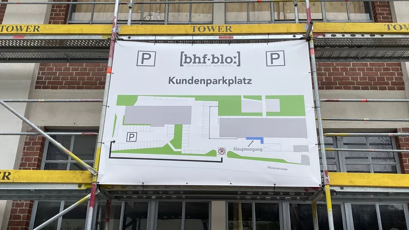An einem Baugerüst hängt ein Banner mit einer Karte, auf der die Parksituation beschrieben wird.