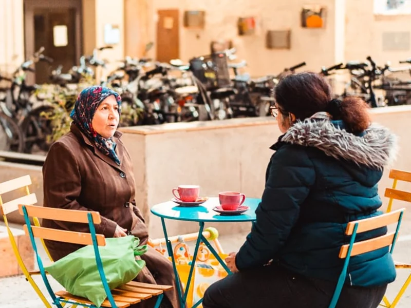 Menschen sitzen draußen neben Fahrradstellplatz mit Kaffeetassen