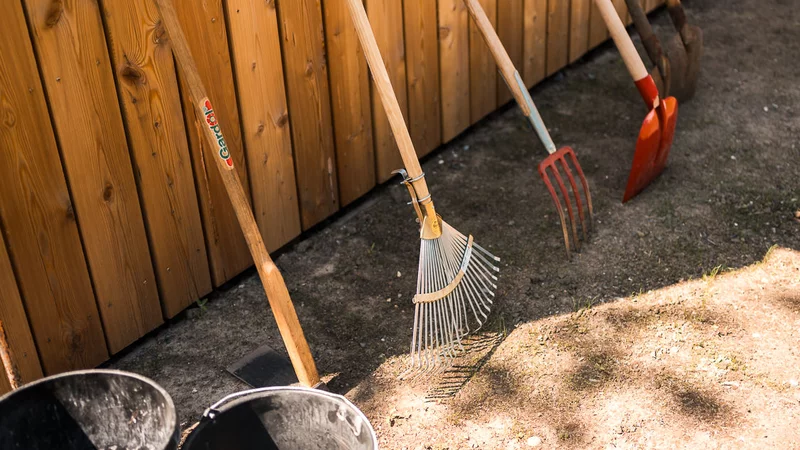 Besen und Eimer an einer Holzwand