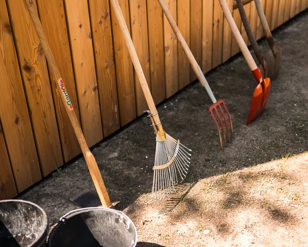 Besen und Eimer an einer Holzwand