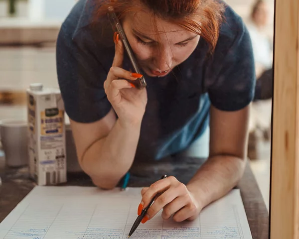 Frau telefoniert stehend, während sie eine Liste durchgeht