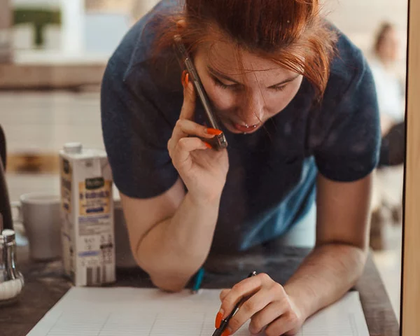 Frau telefoniert stehend, während sie eine Liste durchgeht